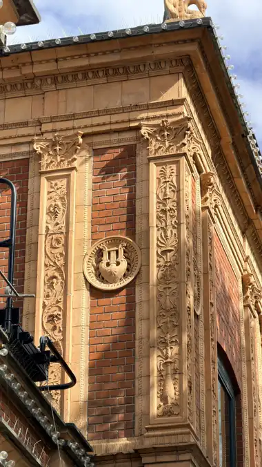 Billede af pavillon lyre medaljon ved sidebygningen, i tegl, mørtel, jern og glas.