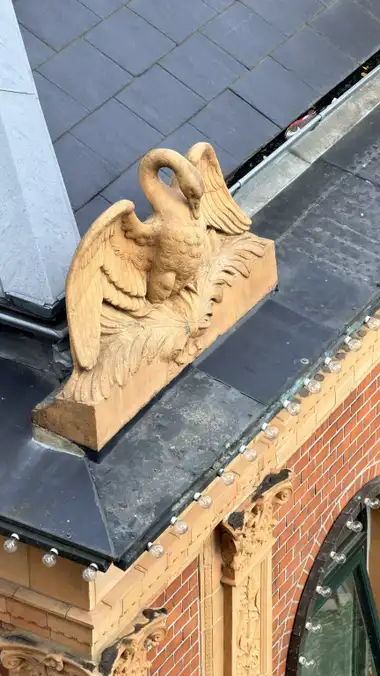 Nærbillede af terrakotta svane tag figur ved sidebygningen, i skifer, zink, tegl og mørtel.